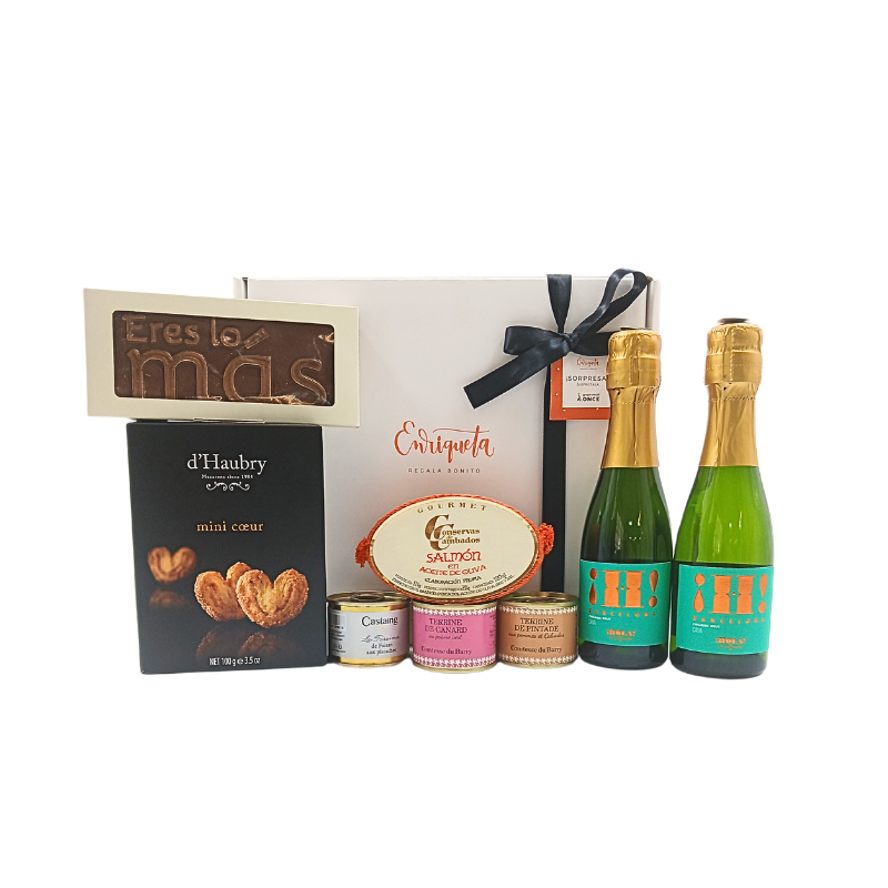 Imagen de una caja blanca con productos gourmet, que son cuatro latas de conservas, dos botellas de cava, una caja de palmeras y un cholate que dice eres lo más image number null